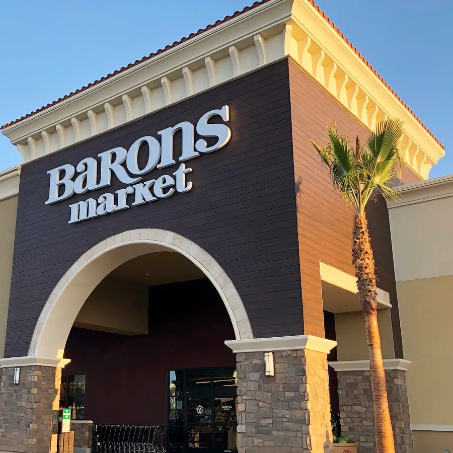 Exterior entrance of Barons Market with signage and palm tree